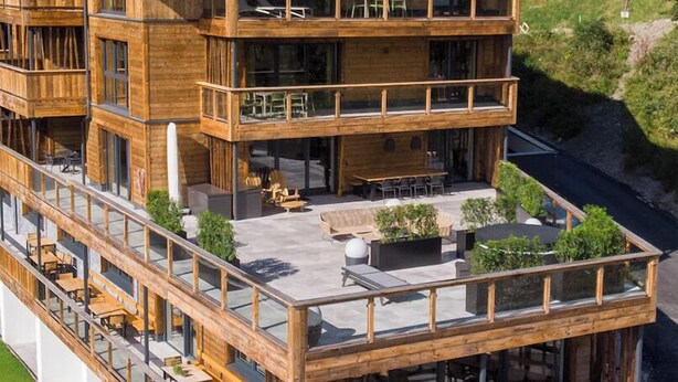 A multi-story wooden building with outdoor seating and a balcony. - Das Förstereck (Viehhofen)