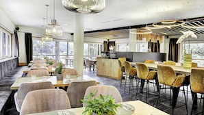 A modern restaurant with a long communal table, individual tables, and comfortable seating. - Das Förstereck (Viehhofen)