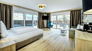 A modern hotel room with a large bed, a desk, a chair, and a television. - Das Förstereck (Viehhofen)