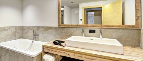 A modern bathroom with a wooden vanity, a large mirror, a bathtub, and a shower.