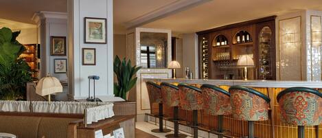 A bar area with a counter, bar stools, and a seating area with a table and chairs.