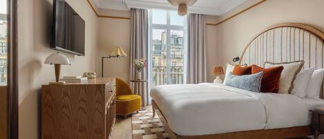 Une chambre d’hôtel avec un grand lit, une télévision, un bureau, une chaise et une vue sur la ville par la fenêtre.
