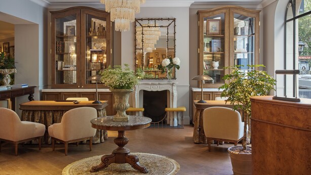 A spacious living room with a fireplace, wooden cabinets, and a chandelier. - Miiro Le Grand Hôtel Cayré (Paris)
