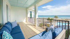 A balcony with a sofa and cushions, a pool, and a view of the ocean. - Oyster House B2 - Sleeps 20 - Beachfront w/ Pool (Gulf Shores)