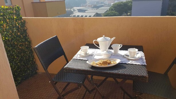 Une table dressée pour le petit-déjeuner sur un balcon, avec vue sur les bâtiments.