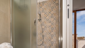 A modern bathroom with a glass-enclosed shower, patterned tiles, and a white toilet. - Casa del Golfo Cascio 3 Secondo Piano (Castellammare del Golfo)