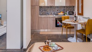 A modern kitchen with a microwave, stove, and a dining area with a table and chairs. - Casa del Golfo Cascio 3 Secondo Piano (Castellammare del Golfo)