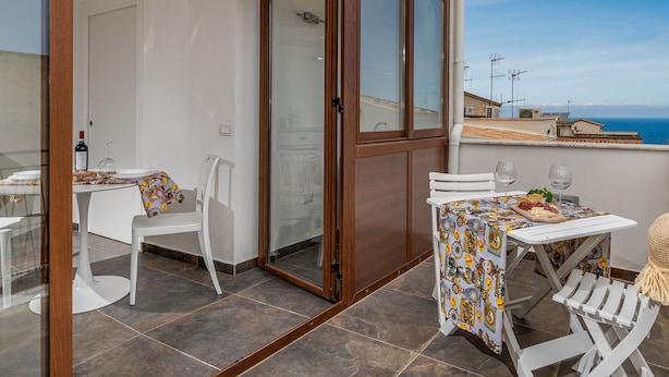 A balcony with a table set for two, a chair, and a view of the sea. - Casa del Golfo Cascio 3 Secondo Piano (Castellammare del Golfo)