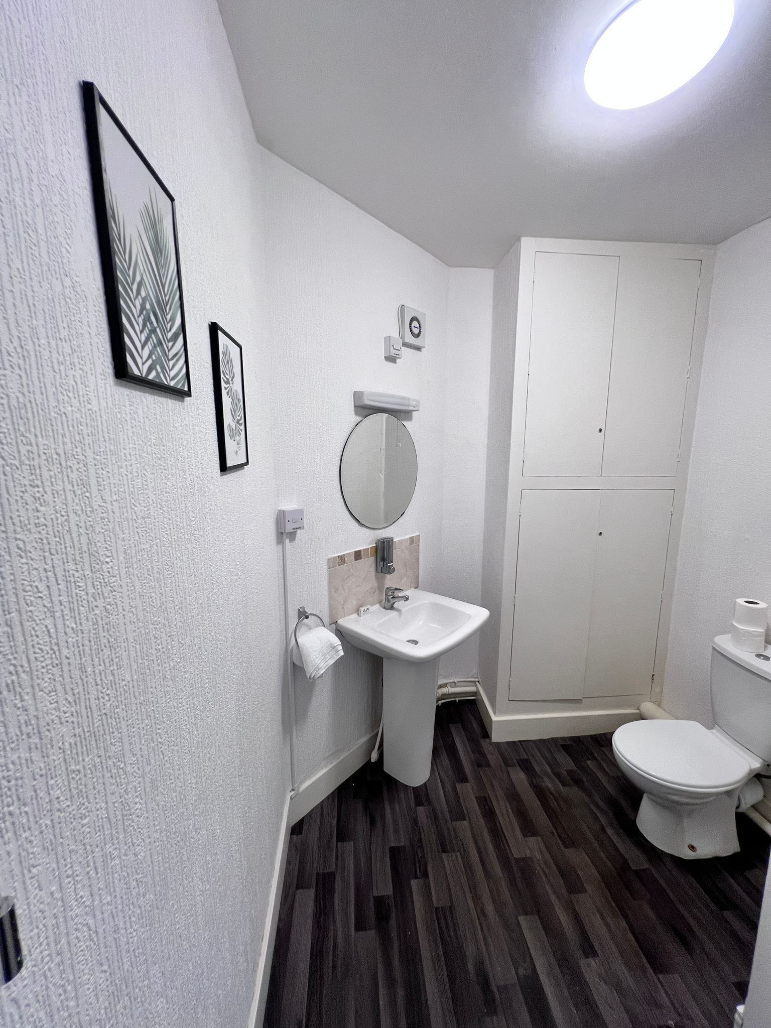A bathroom with a white sink, mirror, toilet, and a towel rack.