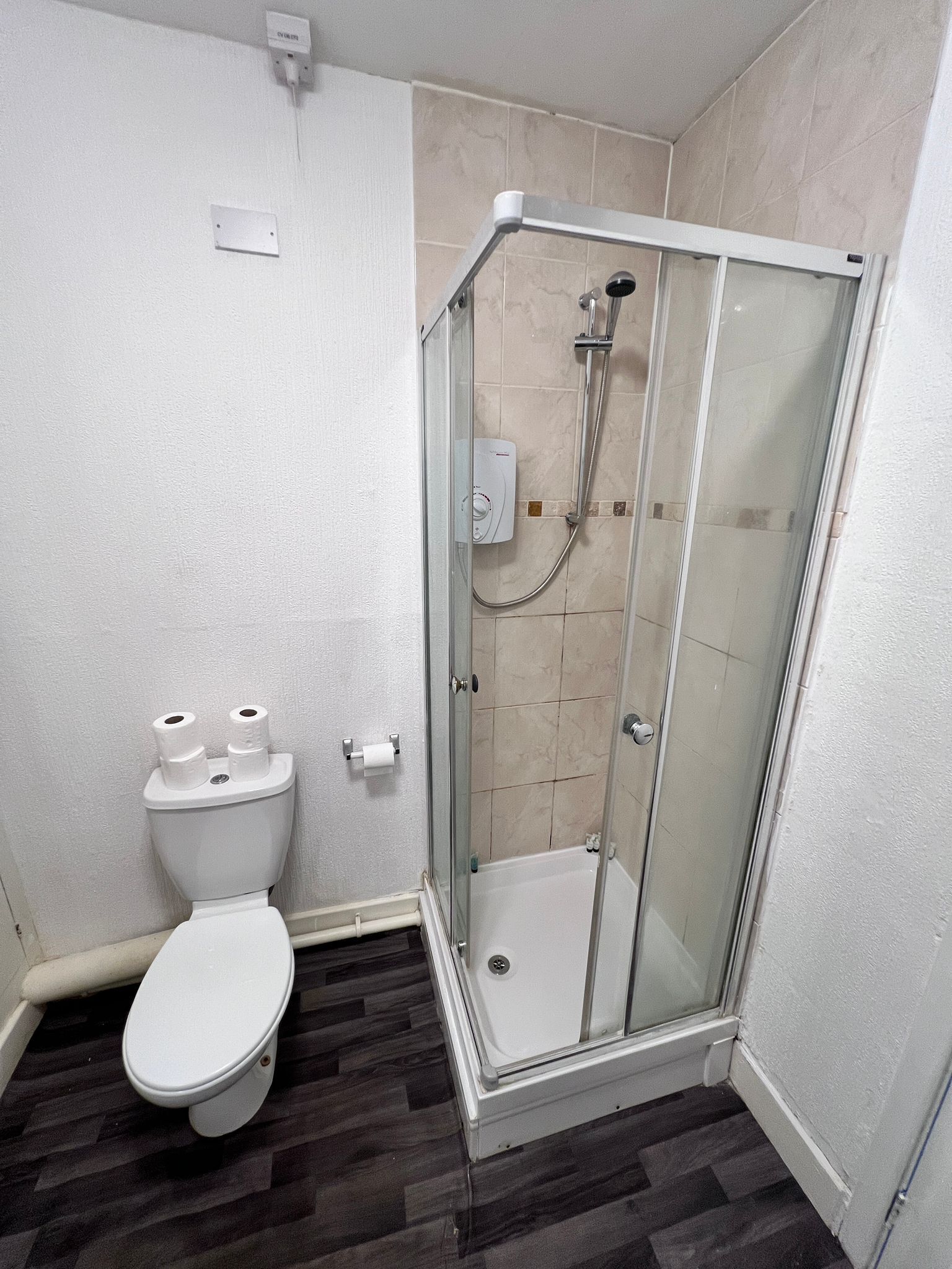 Une salle de bain avec une douche à parois de verre, des toilettes et un lavabo blanc.
