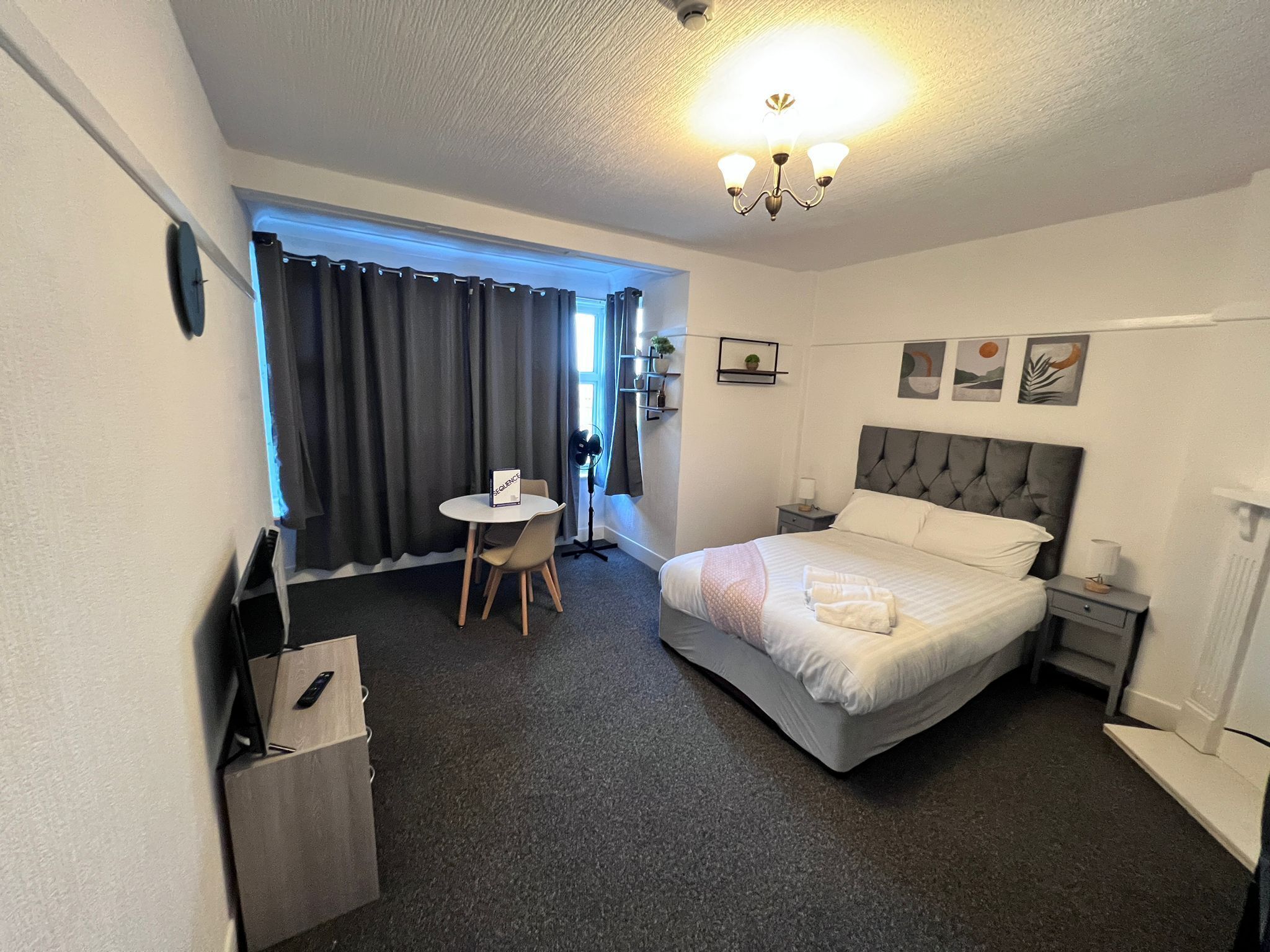 Et hotelværelse med seng, sengeborde, et skrivebord og en stol.