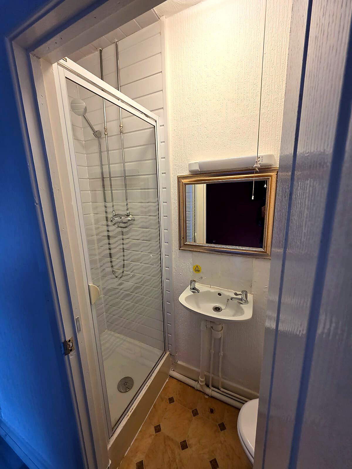 Ein kleines Badezimmer mit Duschkabine aus Glas, Waschbecken und Toilette.