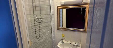 Ein kleines Badezimmer mit Duschkabine aus Glas, Waschbecken und Toilette.