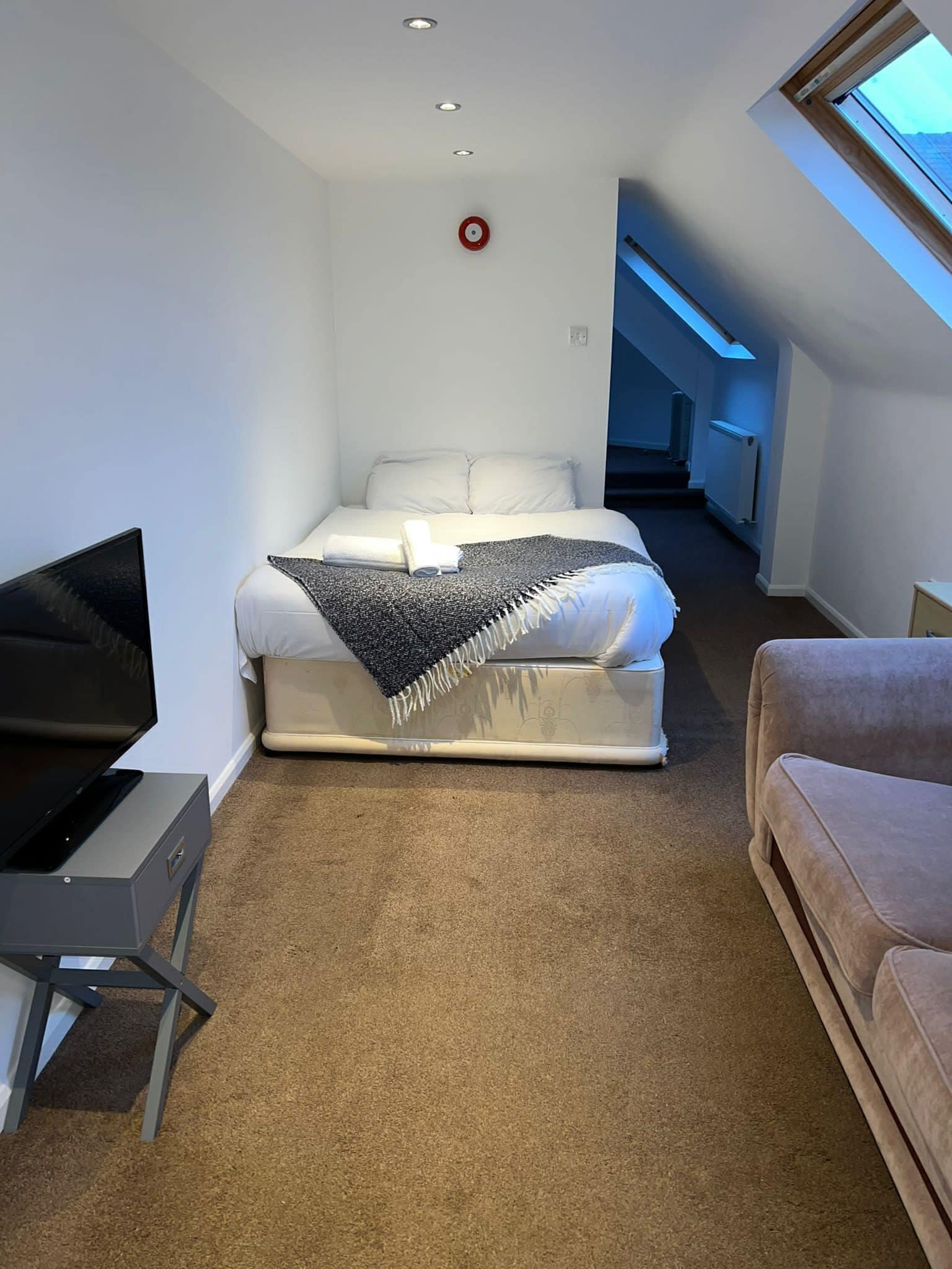 A bedroom with a bed, a TV, and a couch.