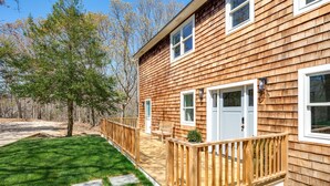 A wooden house with a deck, a lawn, and a tree. - New Hamptons House in Sag harbor + Pool + 8 bedroom (Sag Harbor)