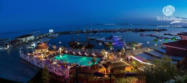 Relax by the pool surrounded by lounge chairs and umbrellas, with easy access to water activities and stunning marina views.
