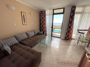 Relax in this stylish living room with a sofa, coffee table, and balcony access to ocean views.
