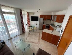 Enjoy a comfortable stay in this apartment with a living area, dining space, and kitchenette, featuring a sofa, dining table, and flat-screen TV.