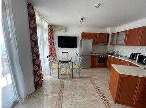 Eine kleine Küche mit Holzausstattung, einem Kühlschrank, einem Backofen und einem Essbereich mit Tisch und Stühlen.