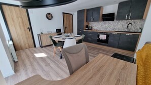 A modern kitchen with dark cabinets, a microwave, and a coffee machine. - Résidence Cosy et Moderne (Morvillars)