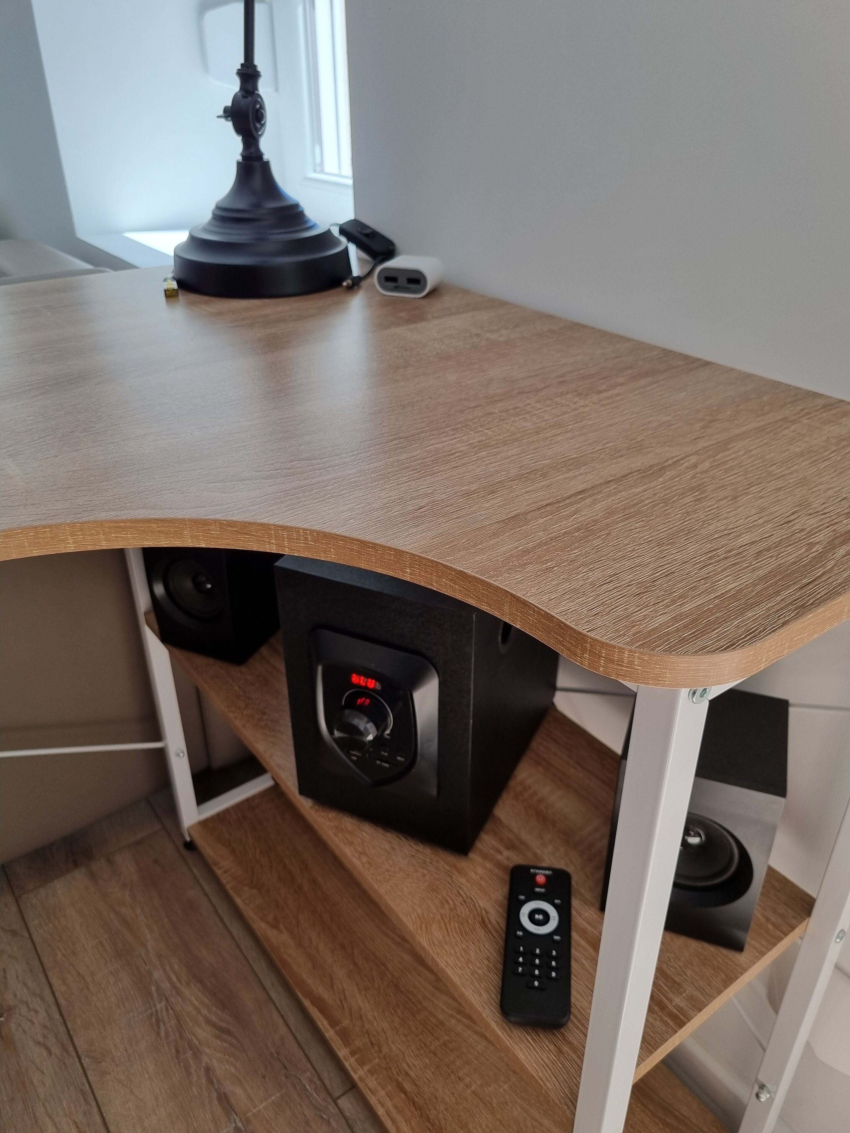 Ein Holztisch mit integriertem Lautsprechersystem, einer Fernbedienung und einer Lampe.