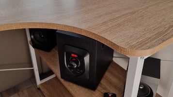 Ein Holztisch mit integriertem Lautsprechersystem, einer Fernbedienung und einer Lampe.
