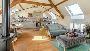 Ein geräumiges Loft mit hohen Decken, freiliegenden Holzbalken, einer Küche mit gefliestem Rücksprung und einer gemütlichen Sitzecke mit Kamin.