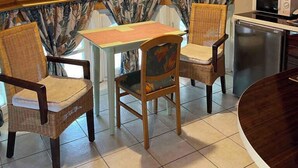 A cozy, wooden-paneled attic room with a dining table and chairs, a chandelier, and a kitchen area with a refrigerator and microwave. - Holiday apartment with air conditioning, WiFi and whirlpool (Siófok)