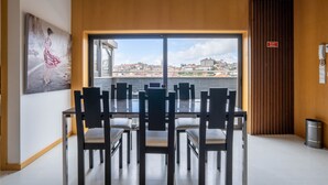 Uma área de refeições com vista para a paisagem urbana através de grandes janelas.