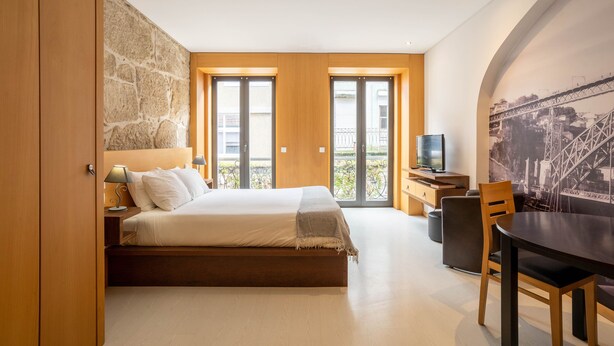 Quarto moderno com uma cama grande, televisão e área de jantar.