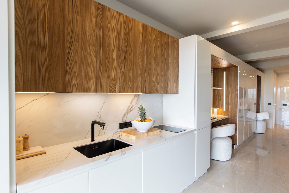 A modern kitchen with a marble countertop, wooden cabinets, and a built-in sink.
