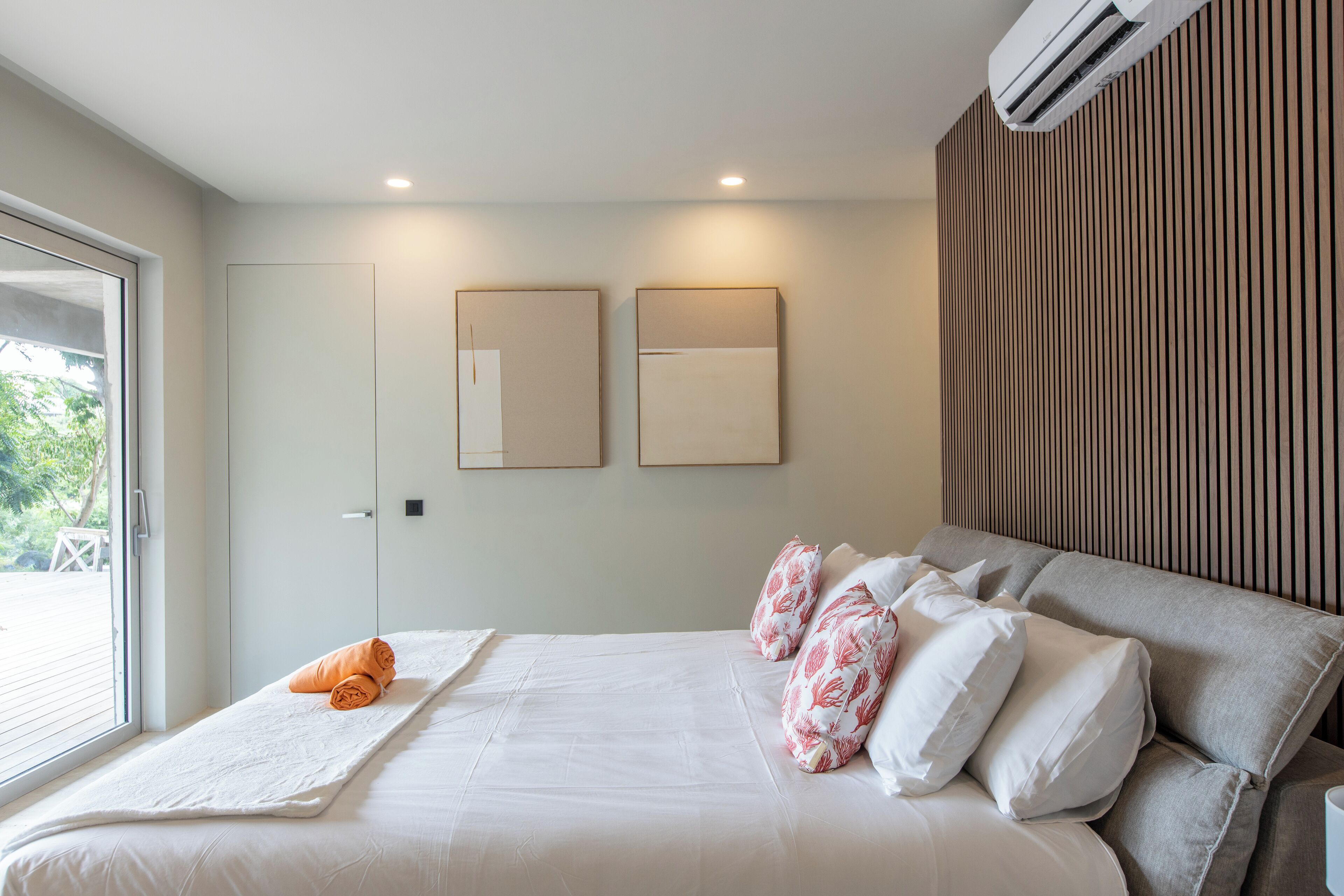 Une chambre d’hôtel moderne avec un grand lit, une fenêtre et un climatiseur fixé au mur.