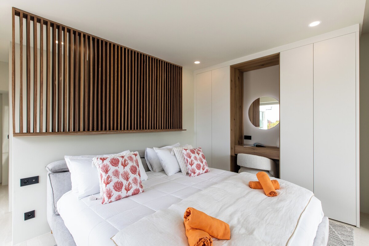 Une chambre d’hôtel moderne avec un grand lit, du linge de lit blanc et un mur recouvert de lattes de bois.