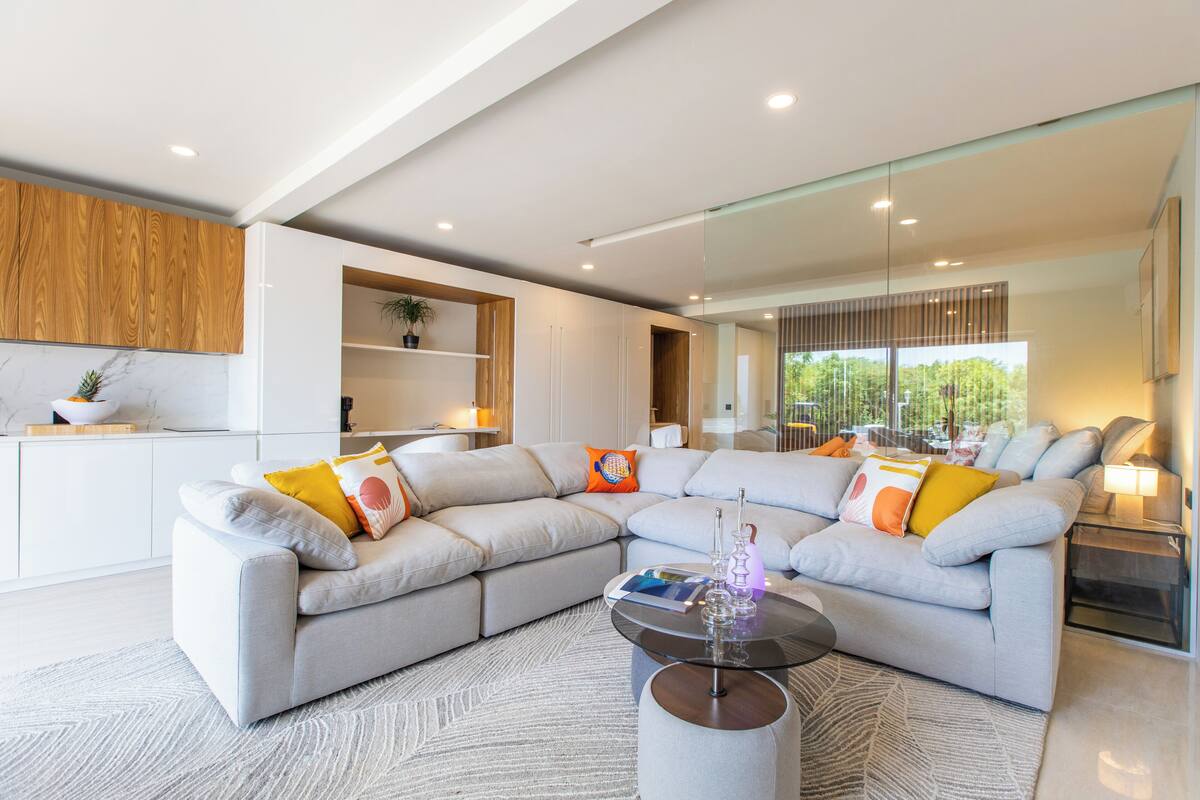 A modern living room with a sectional sofa, a glass coffee table, and a built-in wooden shelf.