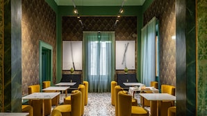 A restaurant with yellow chairs and tables, green walls, and a patterned floor. - Palazzo Savino (Mesagne)