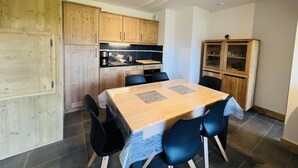 A compact kitchen with wooden cabinets and a dining table with chairs.