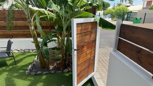 Uma área cercada com uma porta de madeira, um pequeno jardim com grama sintética e um banco.
