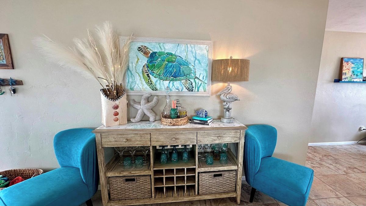 A wooden console table with a framed artwork, a lamp, and decorative items.
