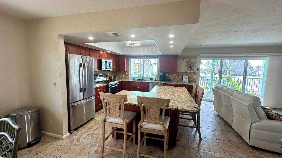 A kitchen with a dining area, a refrigerator, microwave, and a stove.