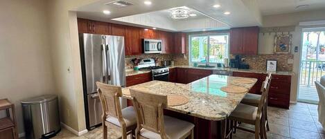 A modern kitchen with a central island, stainless steel appliances, and wooden cabinetry.