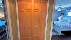 A bedroom with a bed, a ceiling fan, and a wardrobe.
