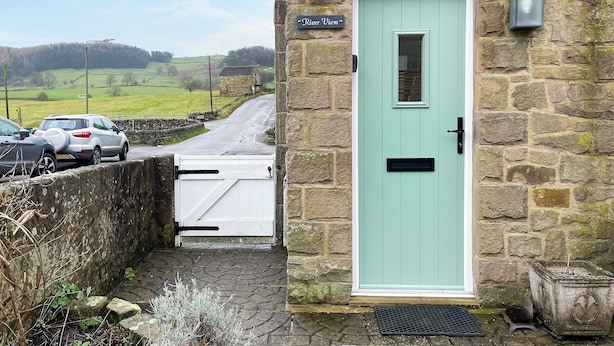 A stone building with a light green door, a small window, and a sign reading "River View".