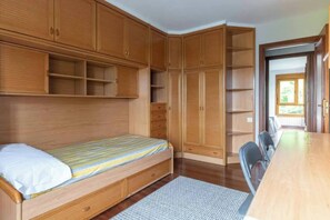 Une chambre à coucher avec un lit, une armoire en bois et un bureau avec une chaise.