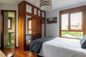 Un dormitori amb un llit, un armari, una finestra i un quadre a la paret.