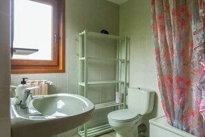 Un bany amb un lavabo blanc, vàter i plat de dutxa.