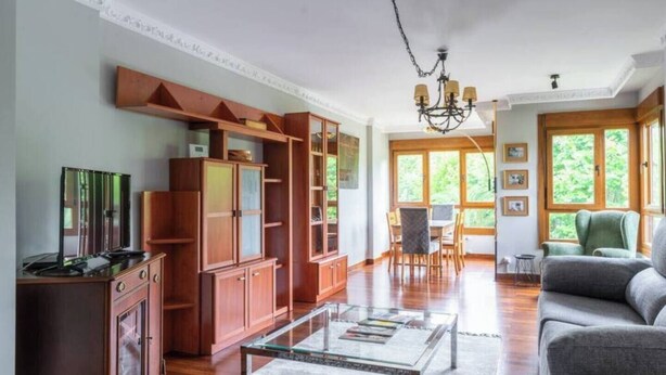 A spacious living room with a wooden cabinet, a glass coffee table, and a sofa. - Apartamento Playa del Sardinero (Santander)