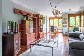 Un salon spacieux avec un meuble en bois, une table basse en verre et un canapé.