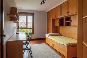 Ein gemütliches Schlafzimmer mit einem Einzelbett, einem Schreibtisch und integrierten Holzregalen.