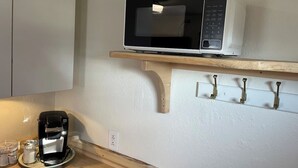 Una cucina con un forno a microonde su uno scaffale, una macchina da caffè e un piano di lavoro in legno.