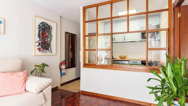 Una habitación con ventana de madera, sofá blanco y extintor en la pared.